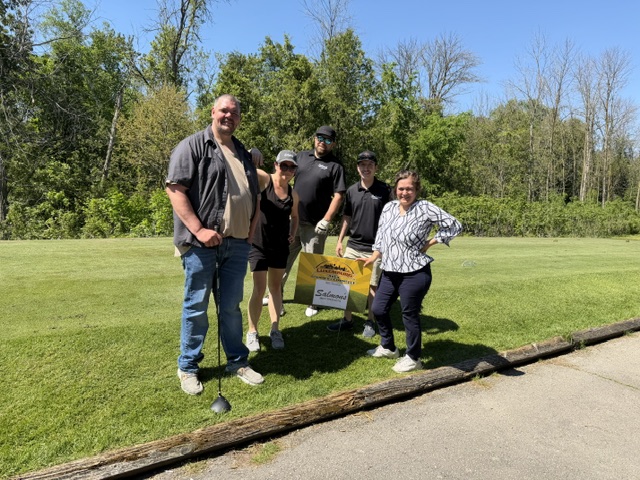 Golfers posed by Salmon's sign