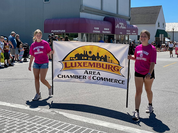 Two girls holding Luxemburg Chamber of Commerce sign